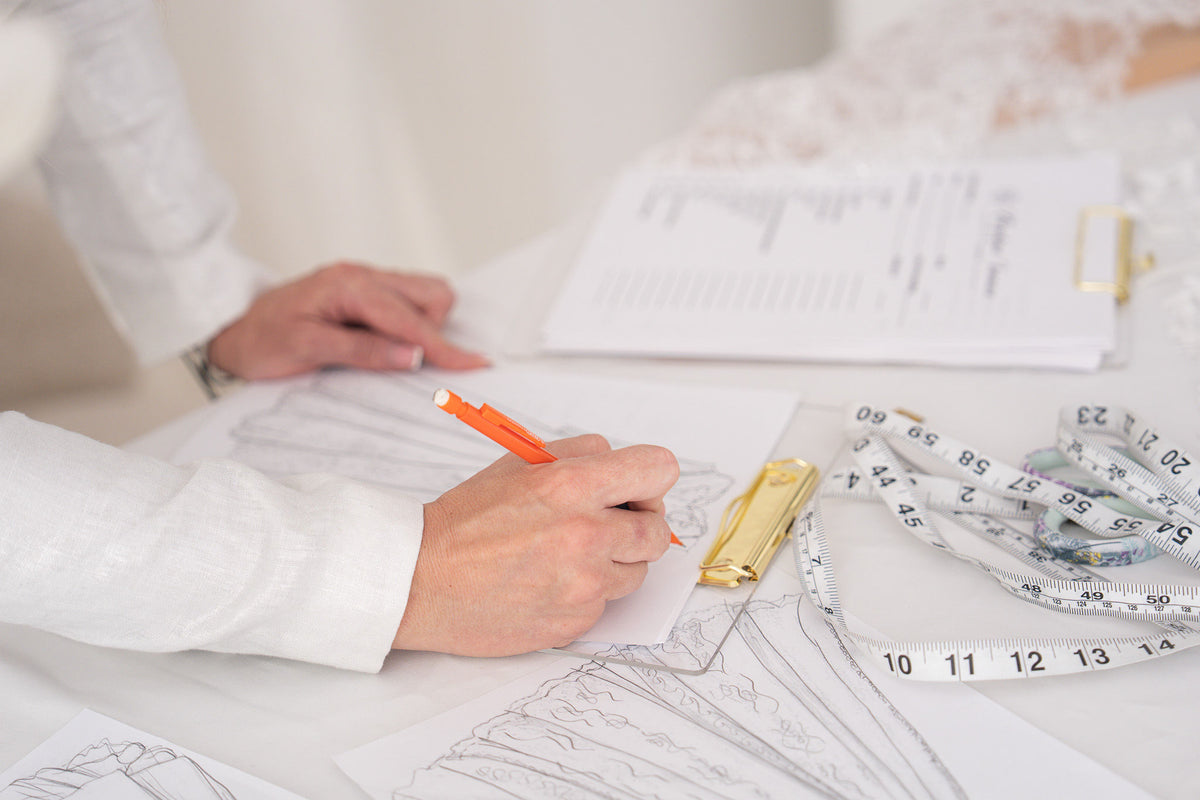 Khrystyna sketching a custom gown, with fabrics and lace